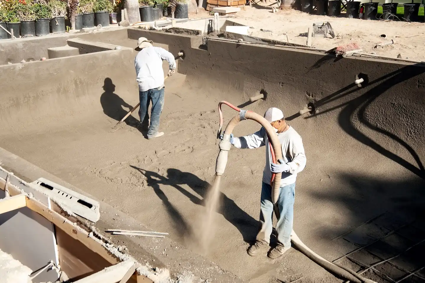 Construction crew spraying gunite on a new pool form.